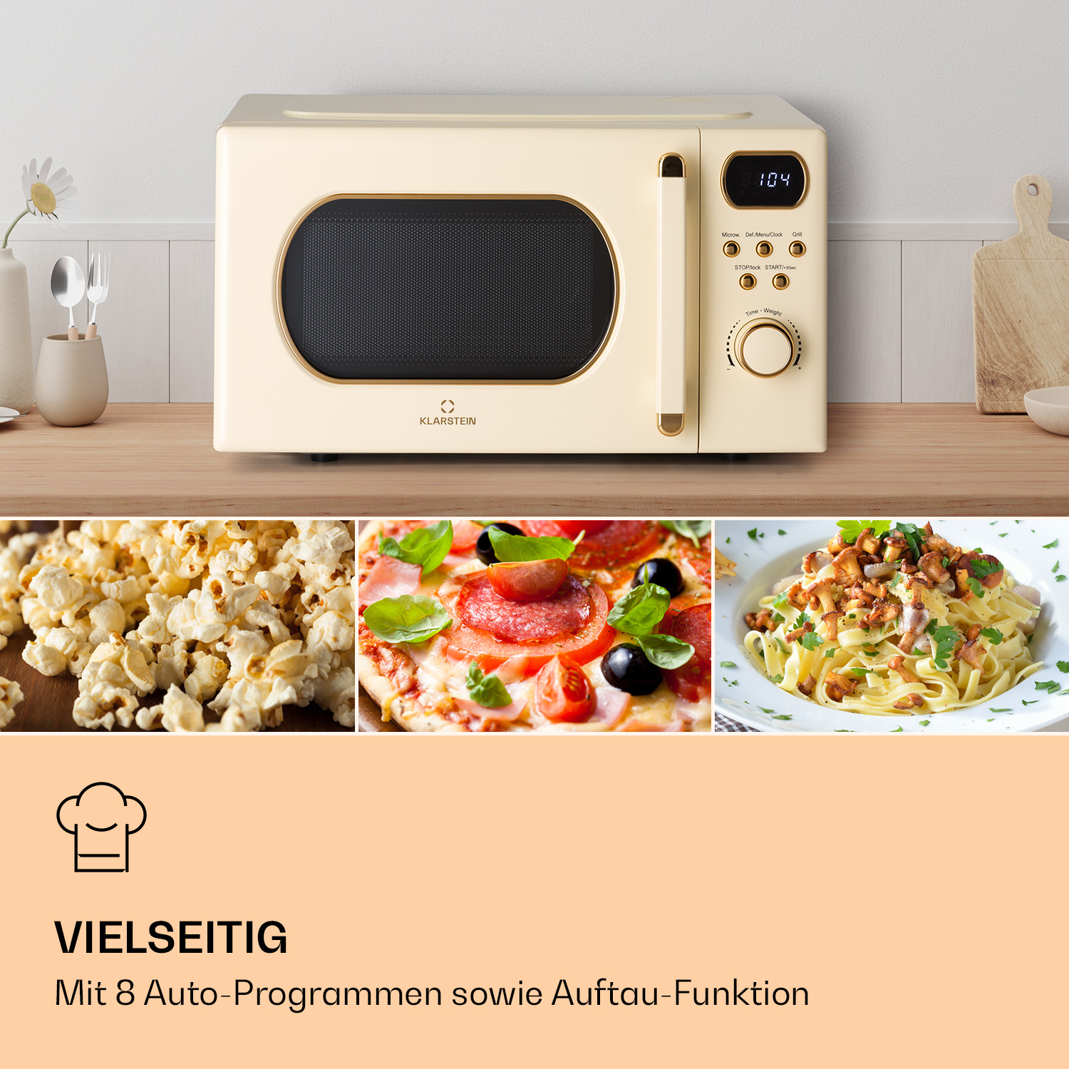 Eine cremefarbene Mikrowelle steht auf einem Holztisch neben Popcorn, Pizza und Pasta.