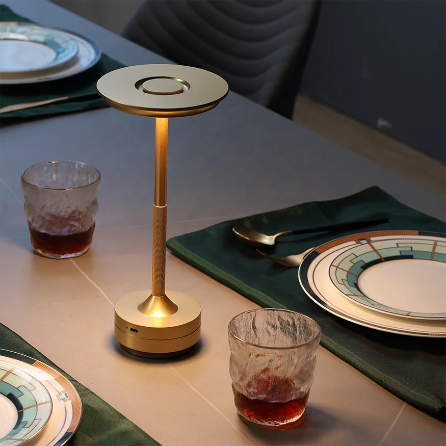 Goldene Tischlampe auf einem Tisch mit Tellern und Gläsern.