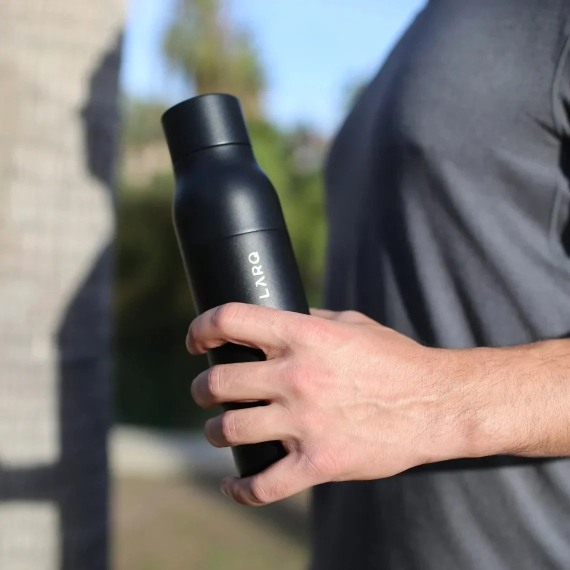 Eine Person hält eine schwarze LARQ-Wasserflasche in der Hand.