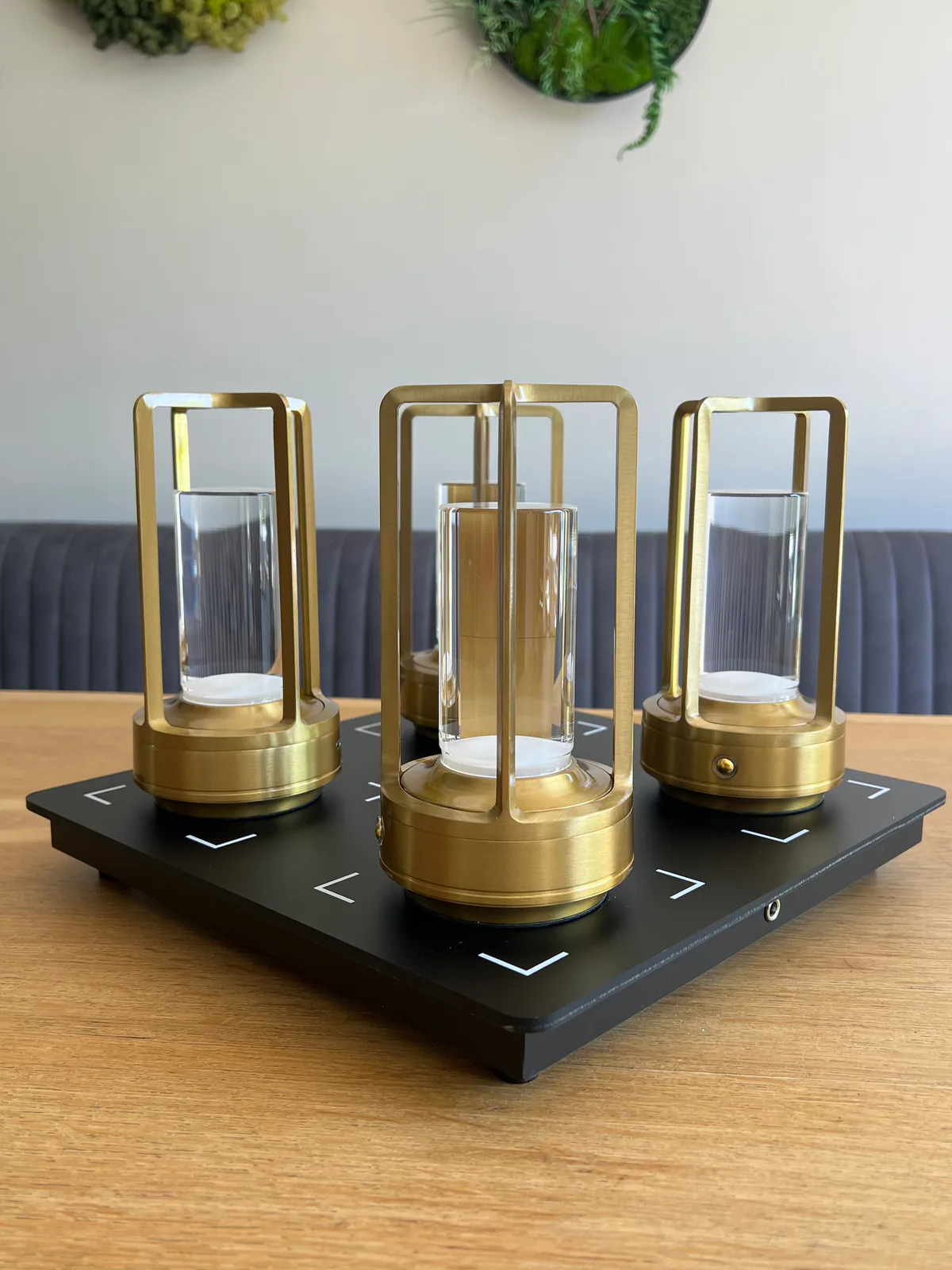 Drei goldene Lampen mit Glaszylindern stehen auf einer schwarzen Platte.