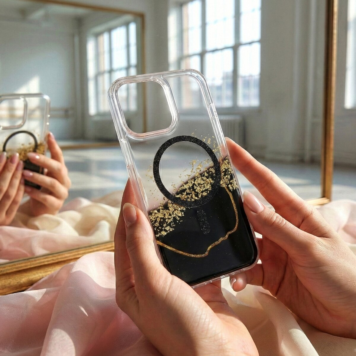 Hände halten eine transparente Handyhülle mit schwarzem Design und Goldflocken.