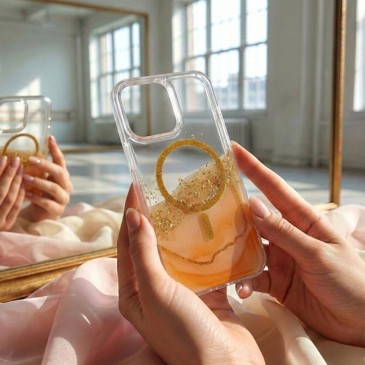 Hände halten eine durchsichtige Handyhülle mit orangefarbener Flüssigkeit und Glitzer.