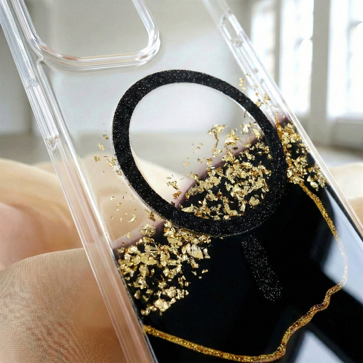 Transparente Handyhülle mit schwarzem Ring und goldenen Flocken.