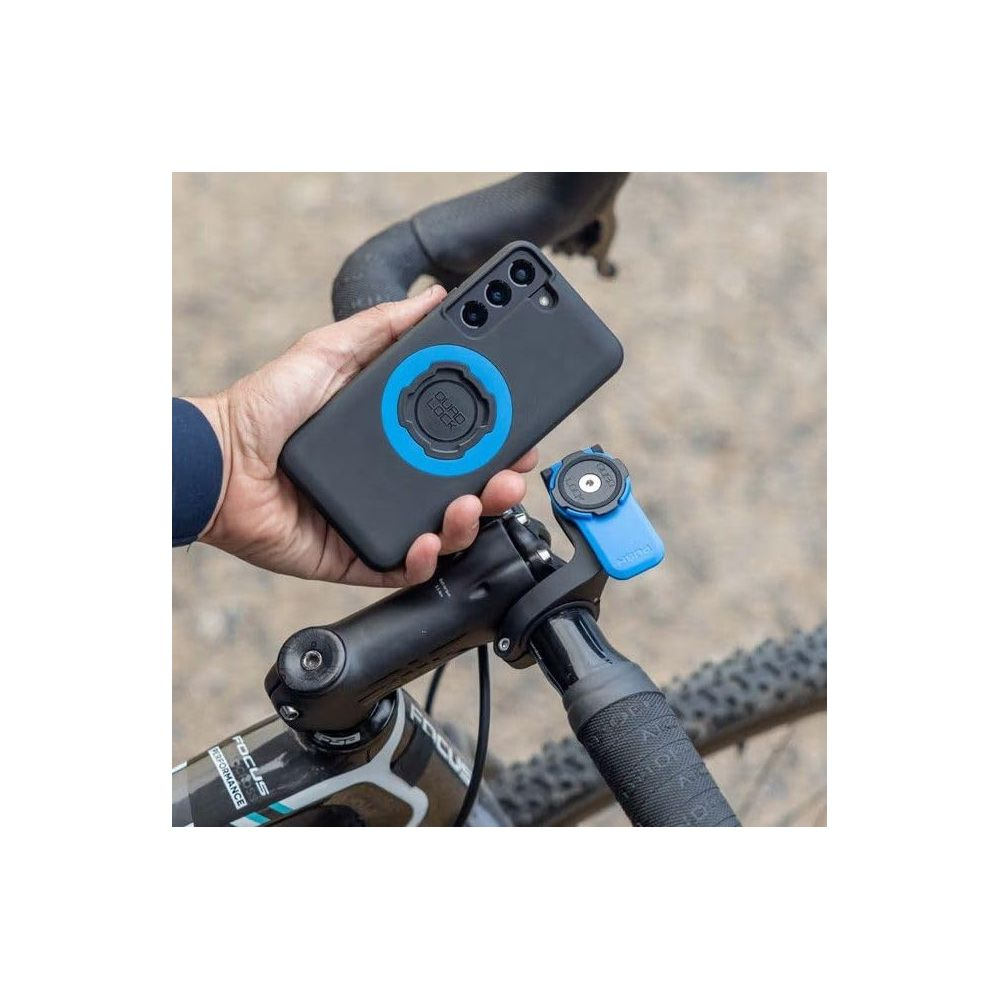 Person hält ein schwarzes Handy mit blauem Ring auf einem Fahrradlenker.