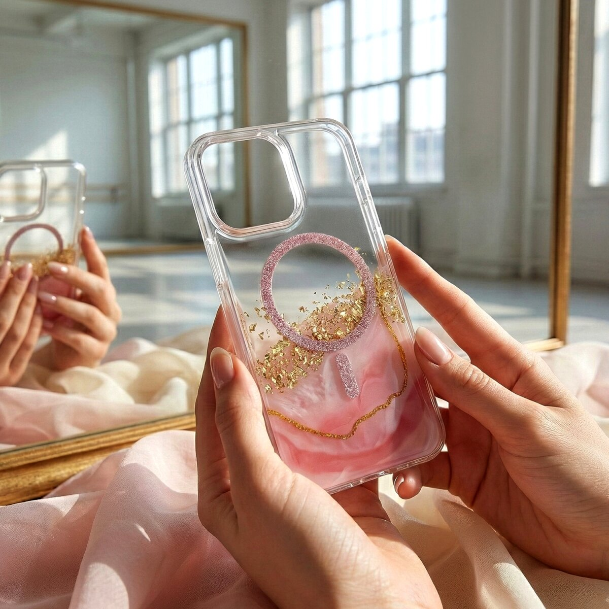 Eine Person hält eine transparente Handyhülle mit rosa Marmormuster und Goldflocken.