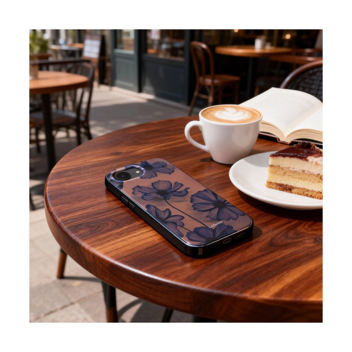 Ein Handy mit Blumenmuster auf einem Holztisch, daneben Kaffee und Kuchen.