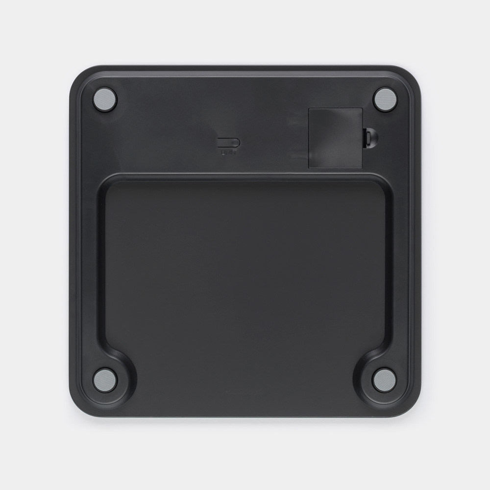 Parte inferiore di una bilancia digitale nera con quattro piedini grigi e vano batteria.