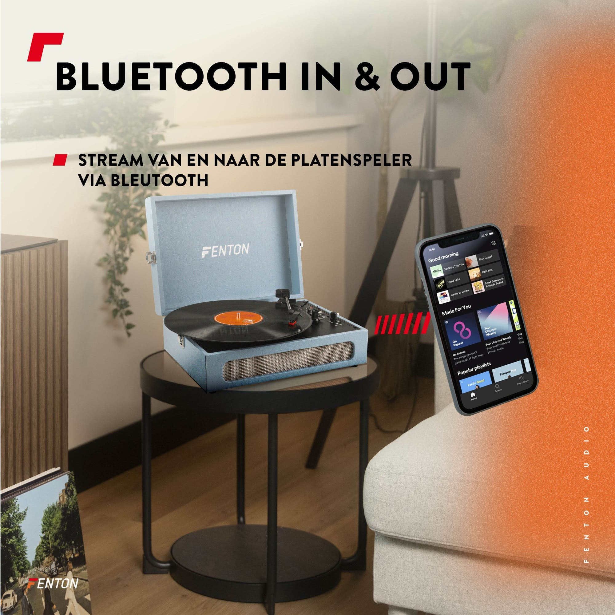 Un tocadiscos Fenton azul con disco de vinilo, junto a un teléfono con una app de música.