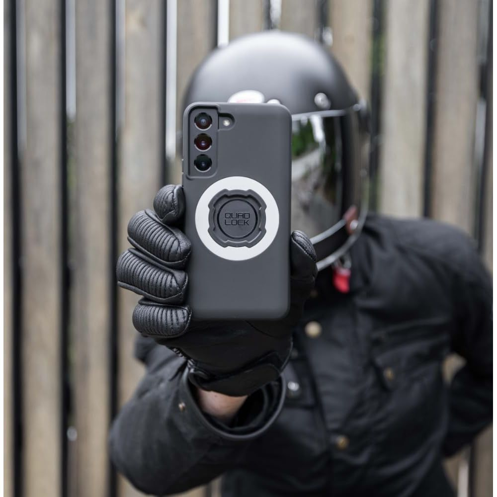Persona con casco e guanti tiene smartphone con supporto Quad Lock.