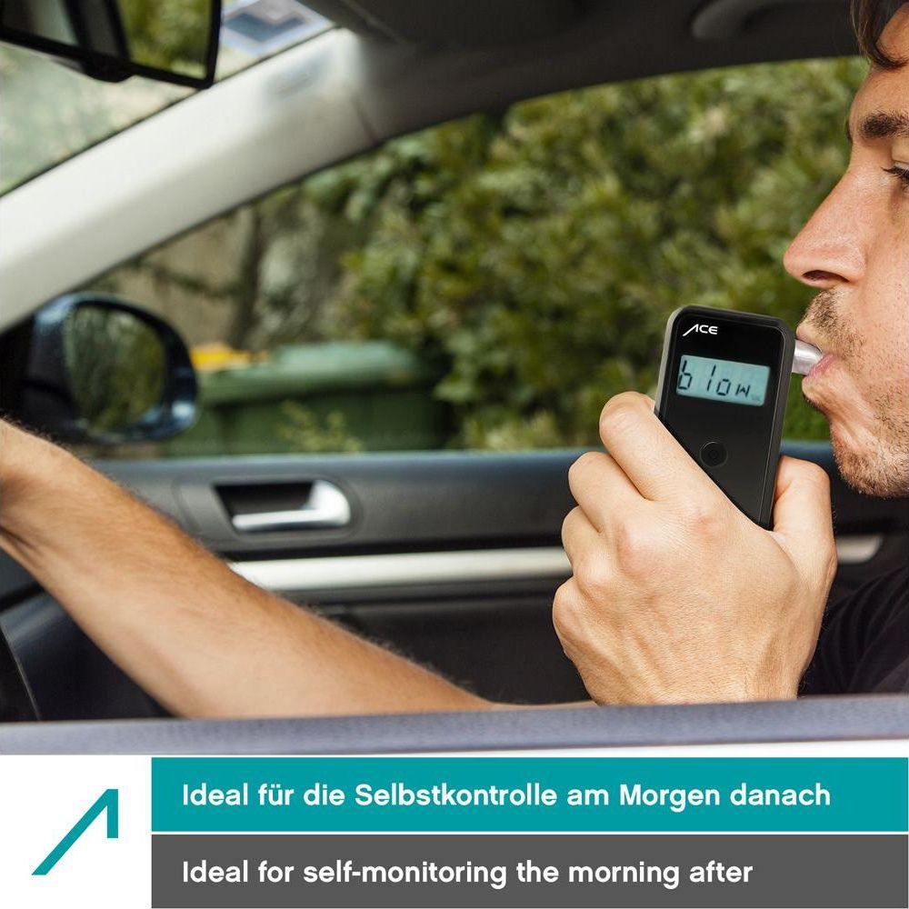 Mann im Auto benutzt Alkoholtester. Draußen grüne Bäume und Mülltonne.