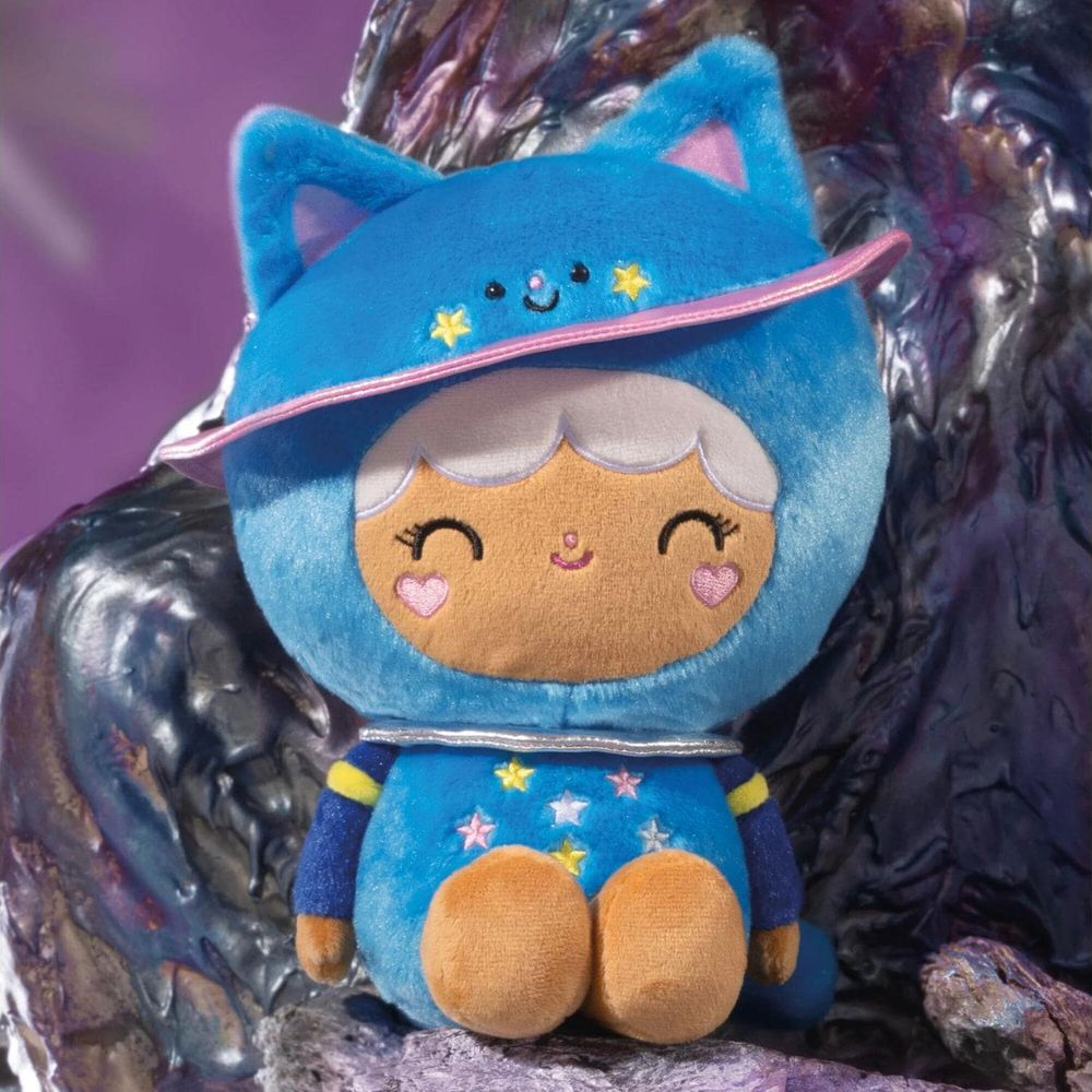 Ein blauer Plüsch-Katzencharakter sitzt auf Felsen mit Sternen und einem Planetenring.