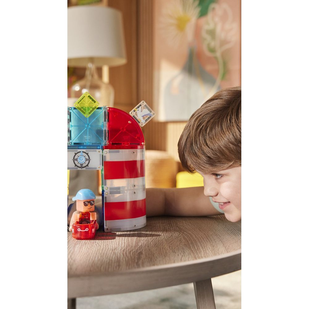 Ein Junge spielt mit magnetischen Bausteinen, die einen Leuchtturm bilden.