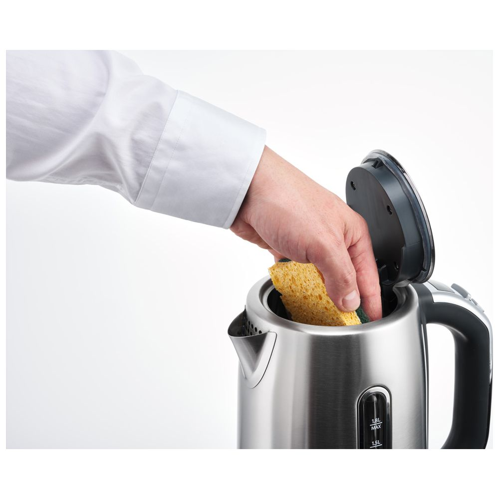 Eine Hand mit einem gelben Schwamm reinigt den Innenraum eines Wasserkochers.