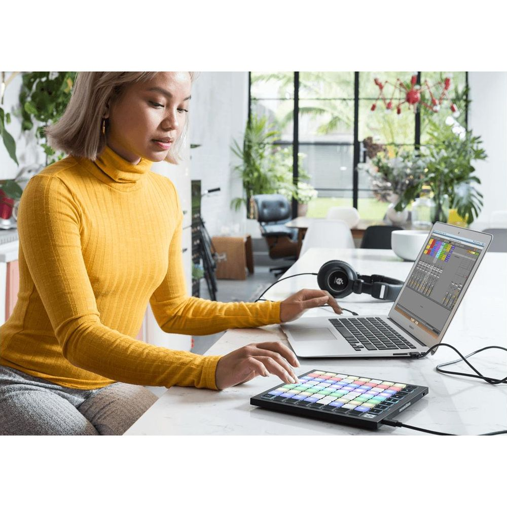 Frau mit gelbem Rollkragenpullover arbeitet an Laptop und Controller.