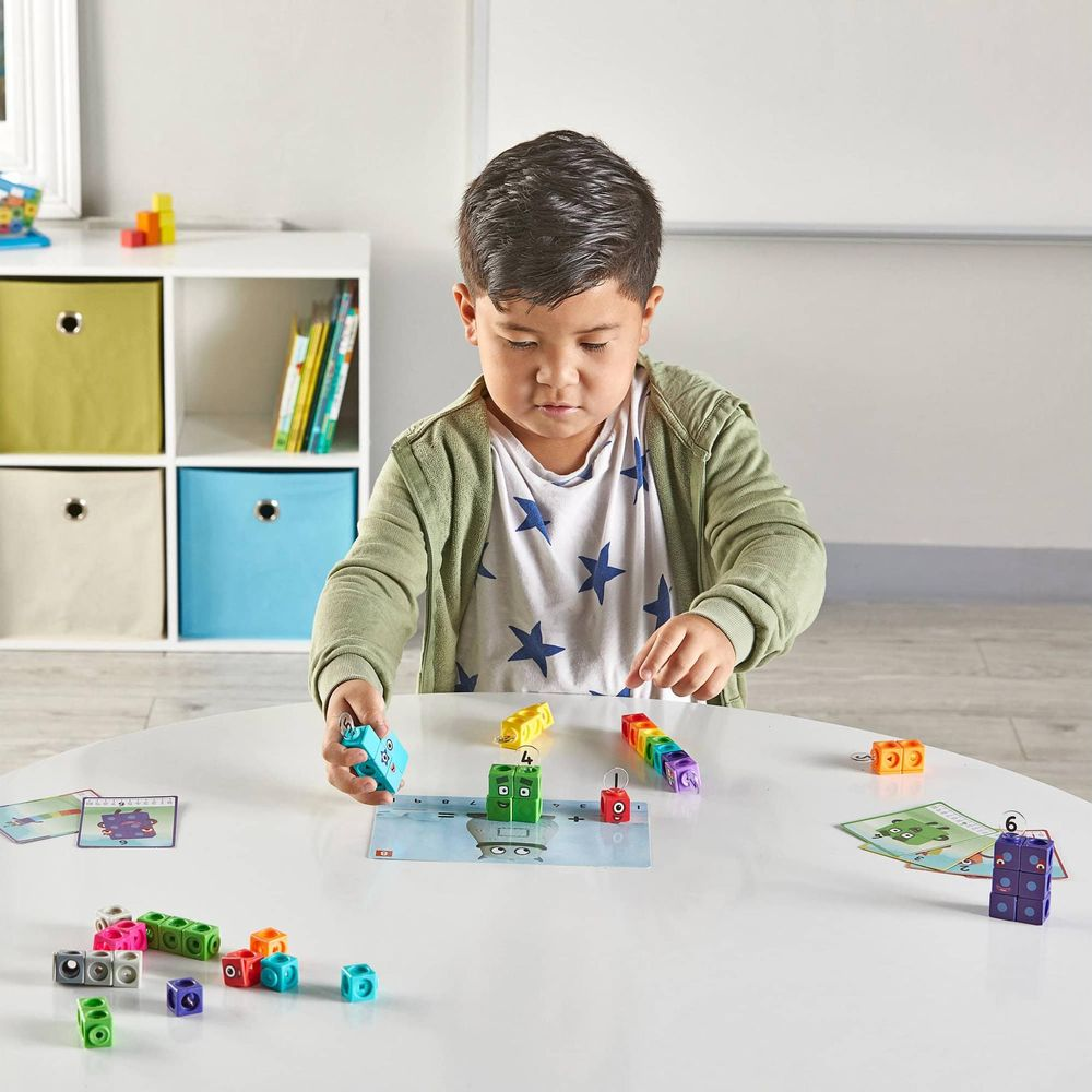 Ein Junge spielt mit bunten Lernblöcken auf einem weißen Tisch.