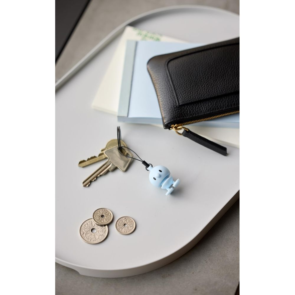 Un amuleto azul con forma de figura cuelga de las llaves junto a monedas y una cartera.