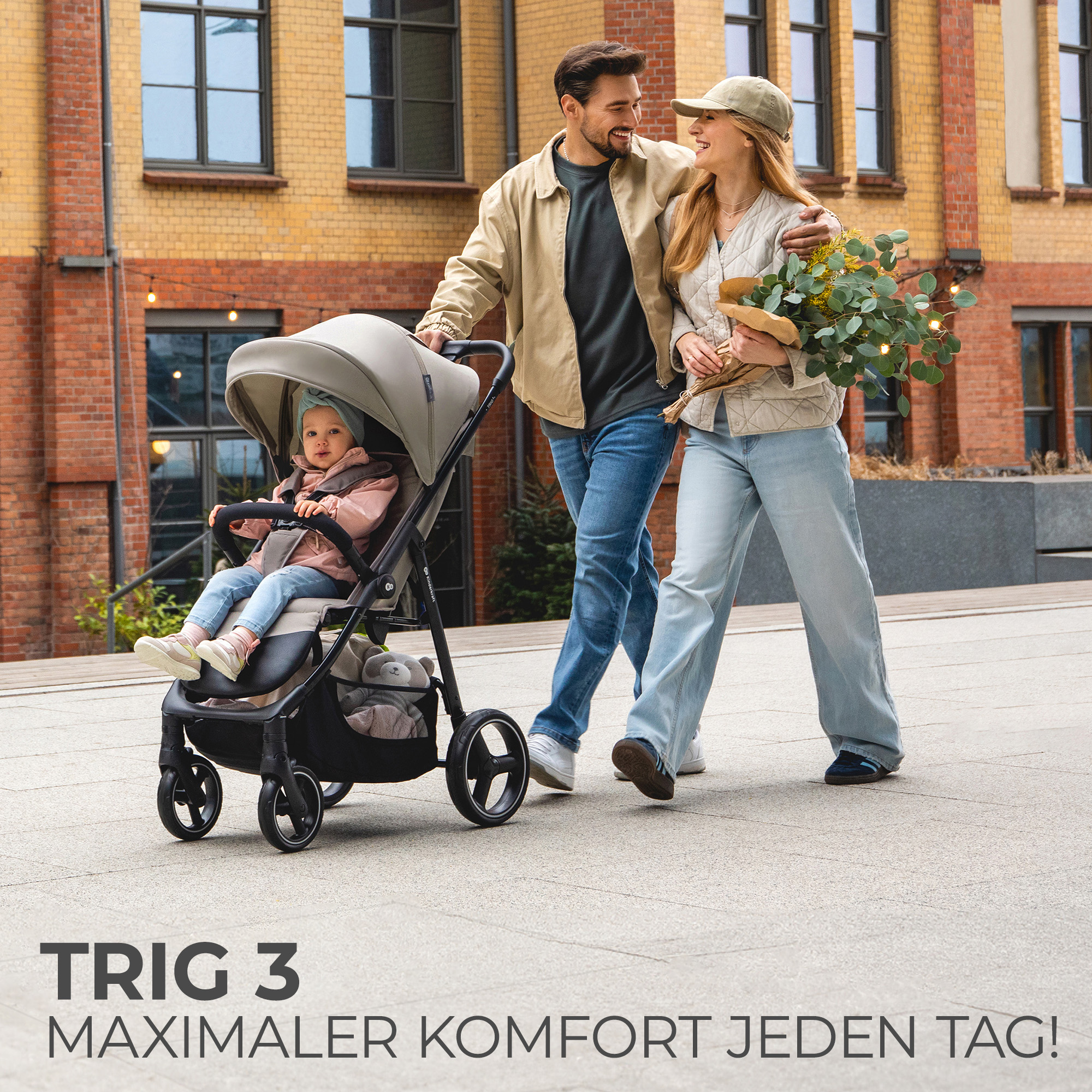 Ein Paar spaziert mit Kinderwagen und Blumen. Ein Baby sitzt im Kinderwagen.