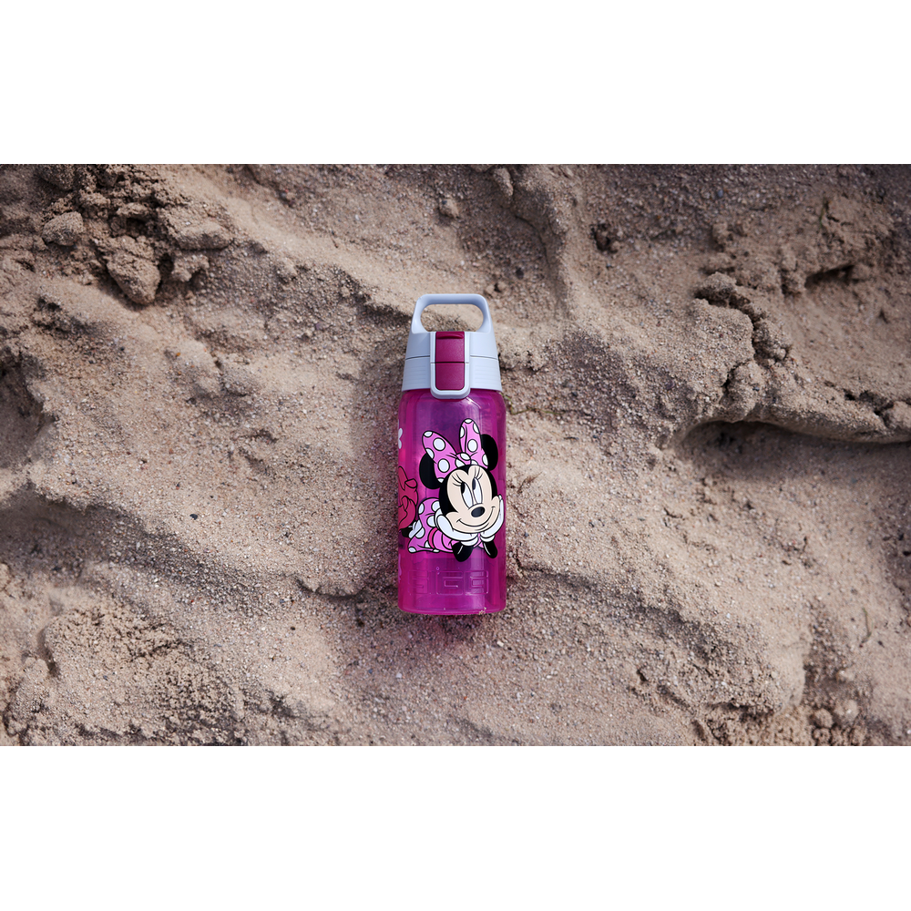 Eine pinke Wasserflasche mit Minnie Maus auf Sand.