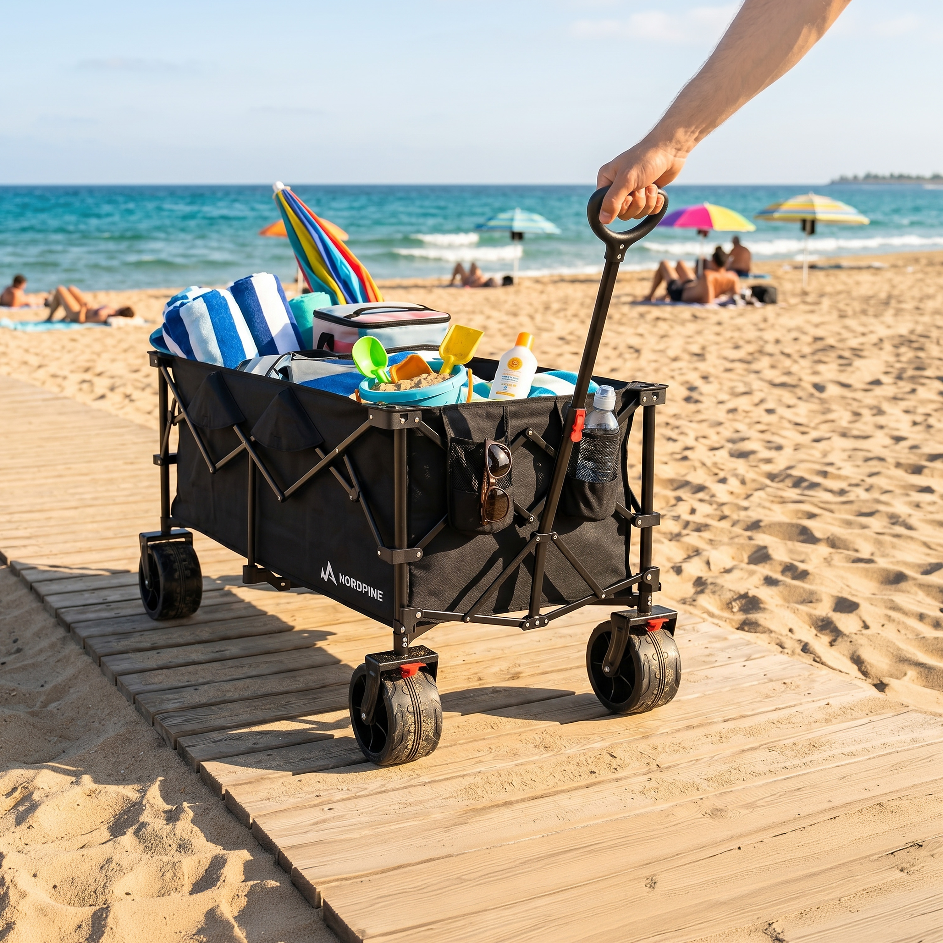 Ein Handwagen mit Strandutensilien auf einem Holzsteg am Strand.