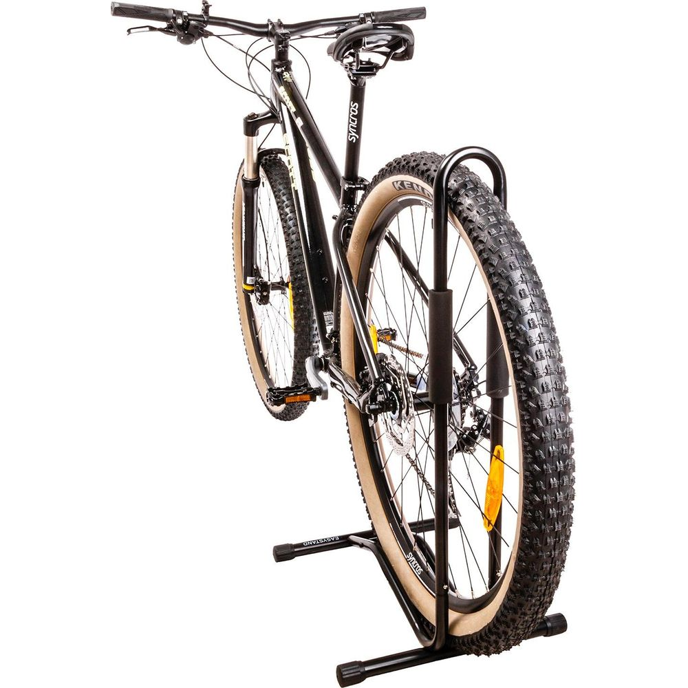 Ein schwarzes Mountainbike mit breiten Reifen steht auf einem schwarzen Fahrradständer.