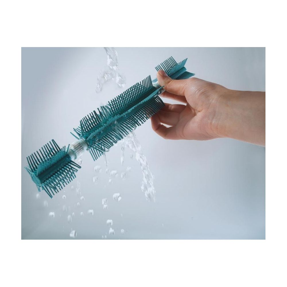 Eine Hand hält eine türkise Bürste unter fließendem Wasser.