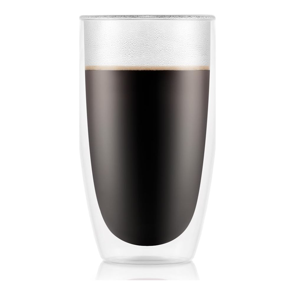 Doppelwandiges Glas mit dunklem Kaffee und Schaum, auf weißem Hintergrund.