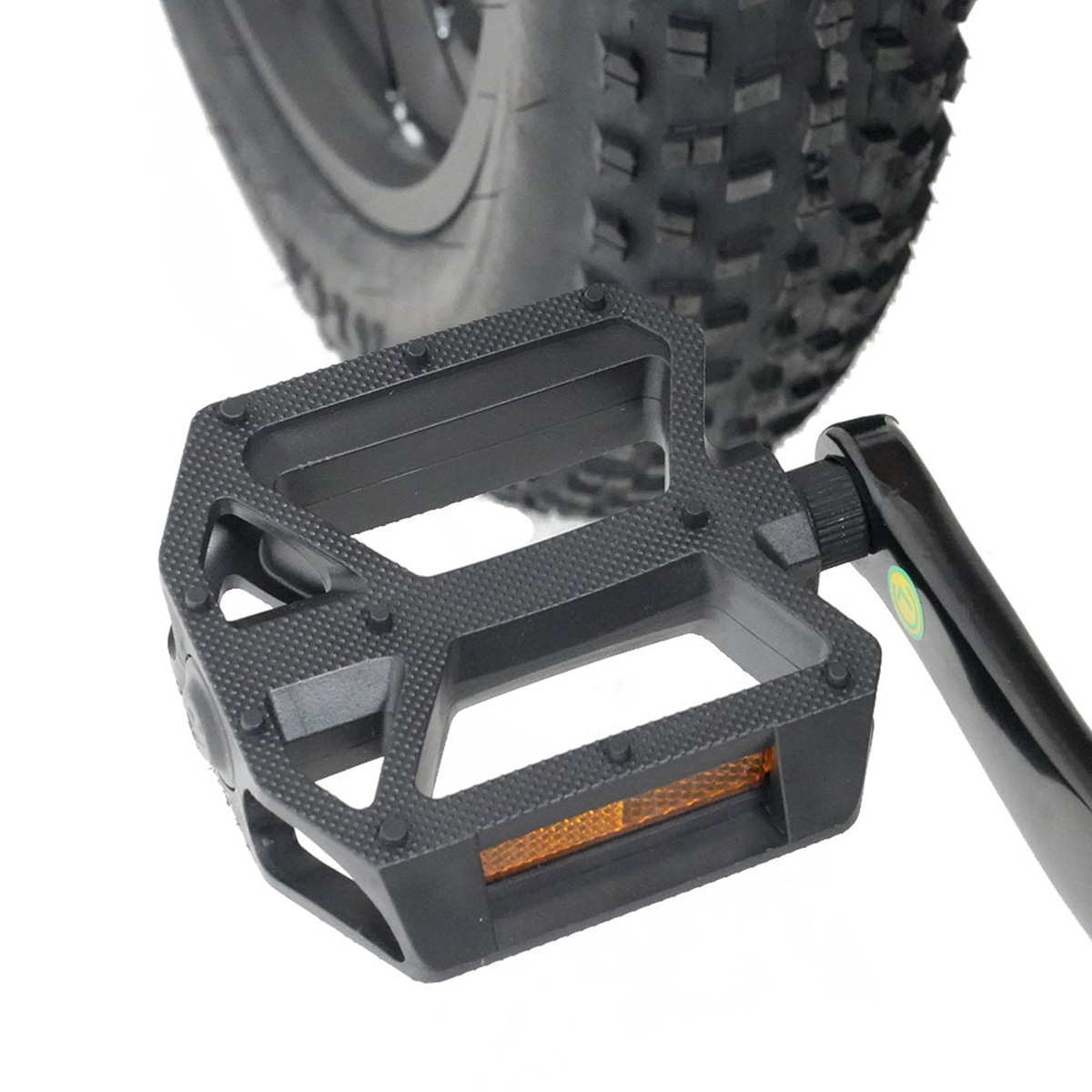 Pedale bicicletta nero con riflettore arancione e ruota sullo sfondo.