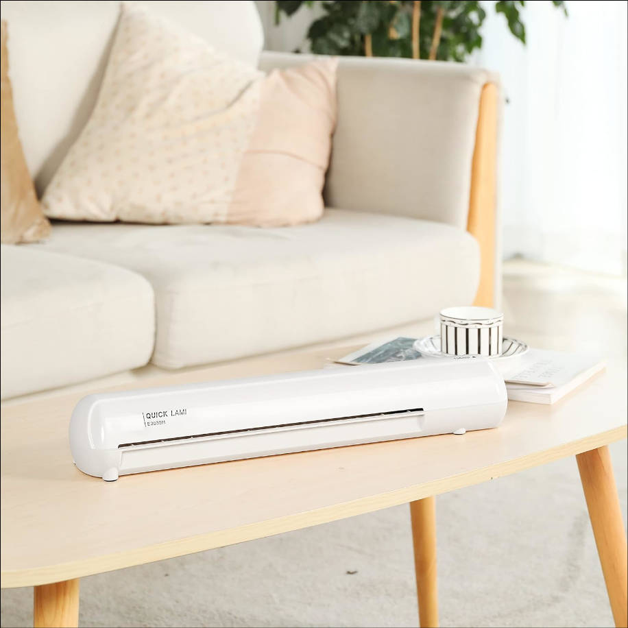 Ein weißer Aktenlaminator steht auf einem Holztisch vor einem Sofa.