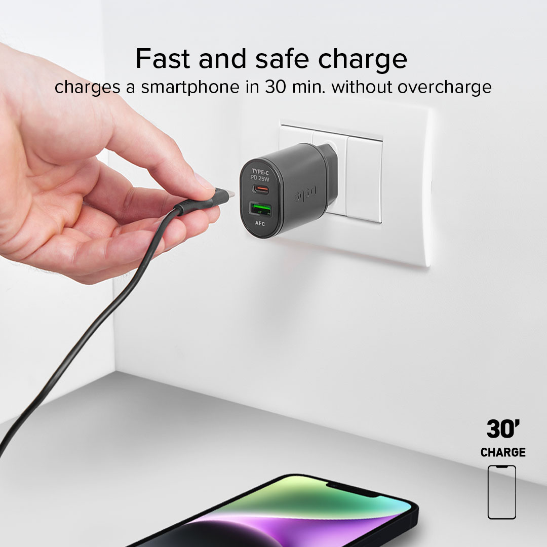 Una mano inserisce un cavo USB-C in un caricatore nero collegato alla presa a muro.