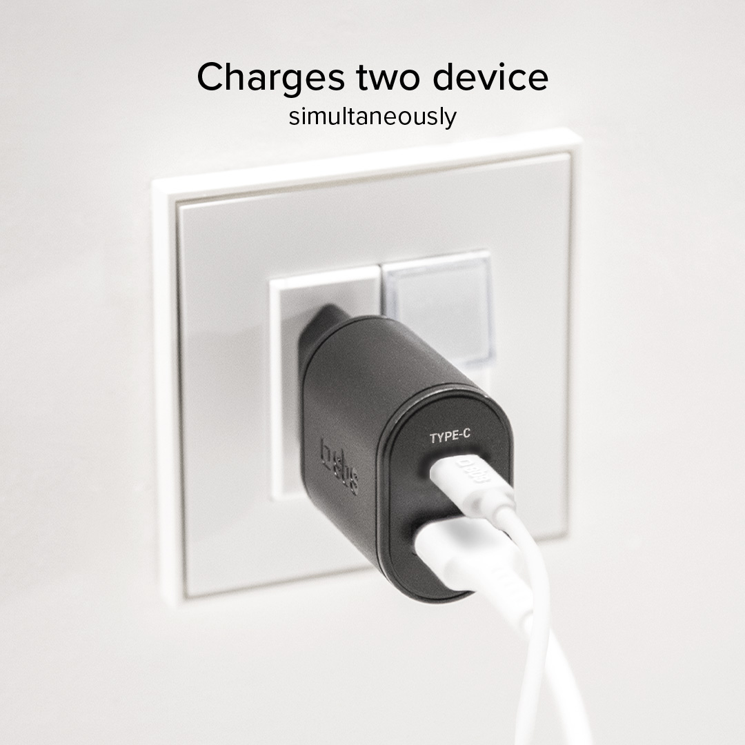 Un adattatore caricatore USB-C nero con due cavi bianchi collegati a una presa a muro.