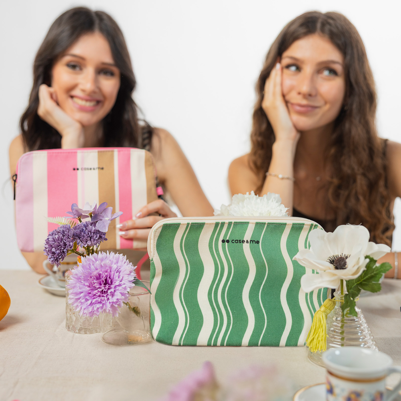 Dos mujeres sentadas en una mesa con neceseres y flores.