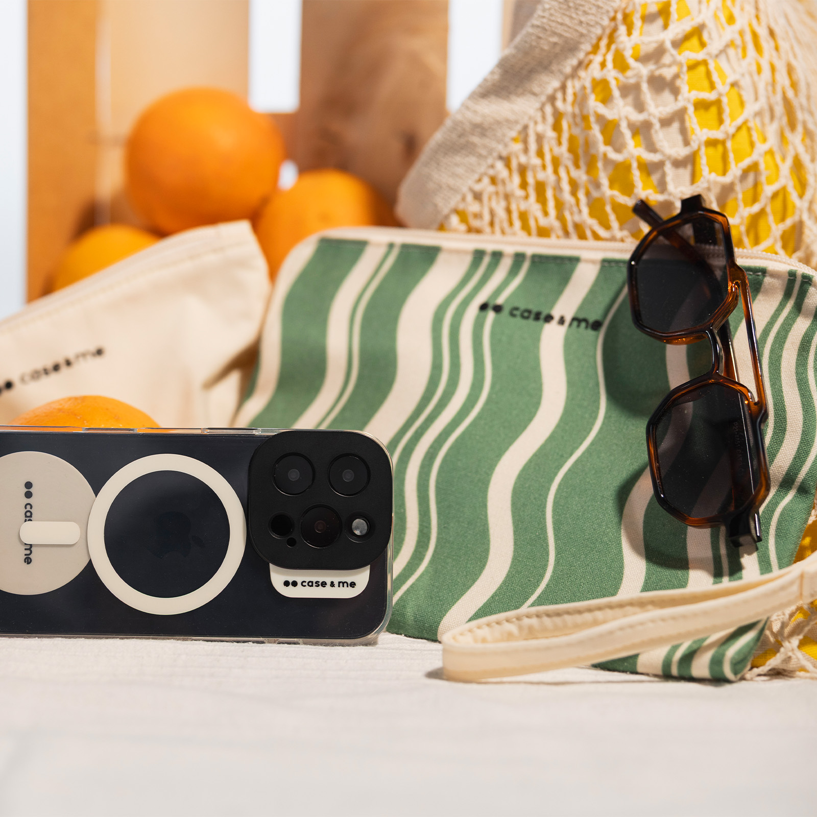 Un smartphone con cámaras, gafas de sol y naranjas sobre un paño blanco.
