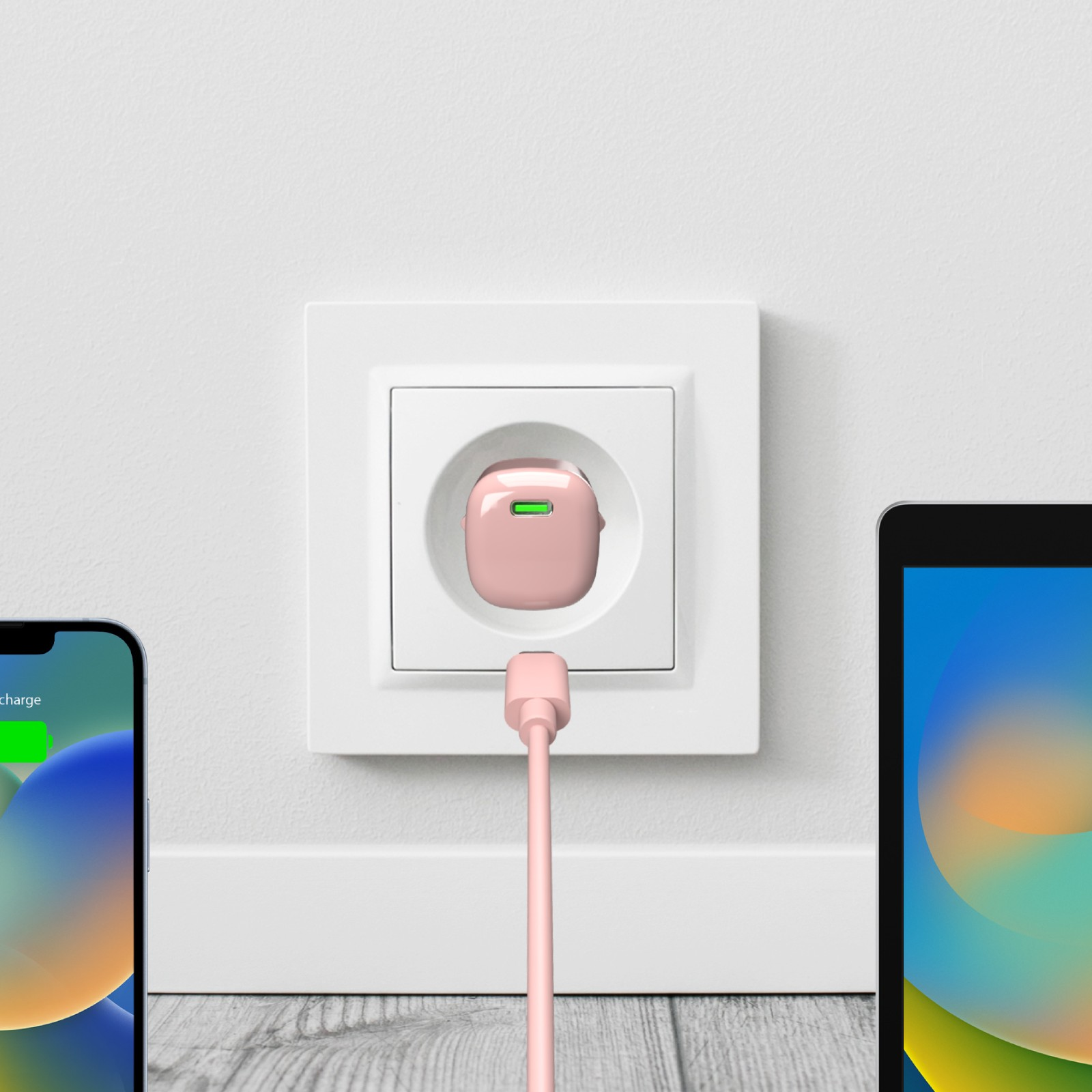 Una spina di ricarica rosa con cavo in una presa a muro bianca. iPhone a sinistra, tablet a destra.