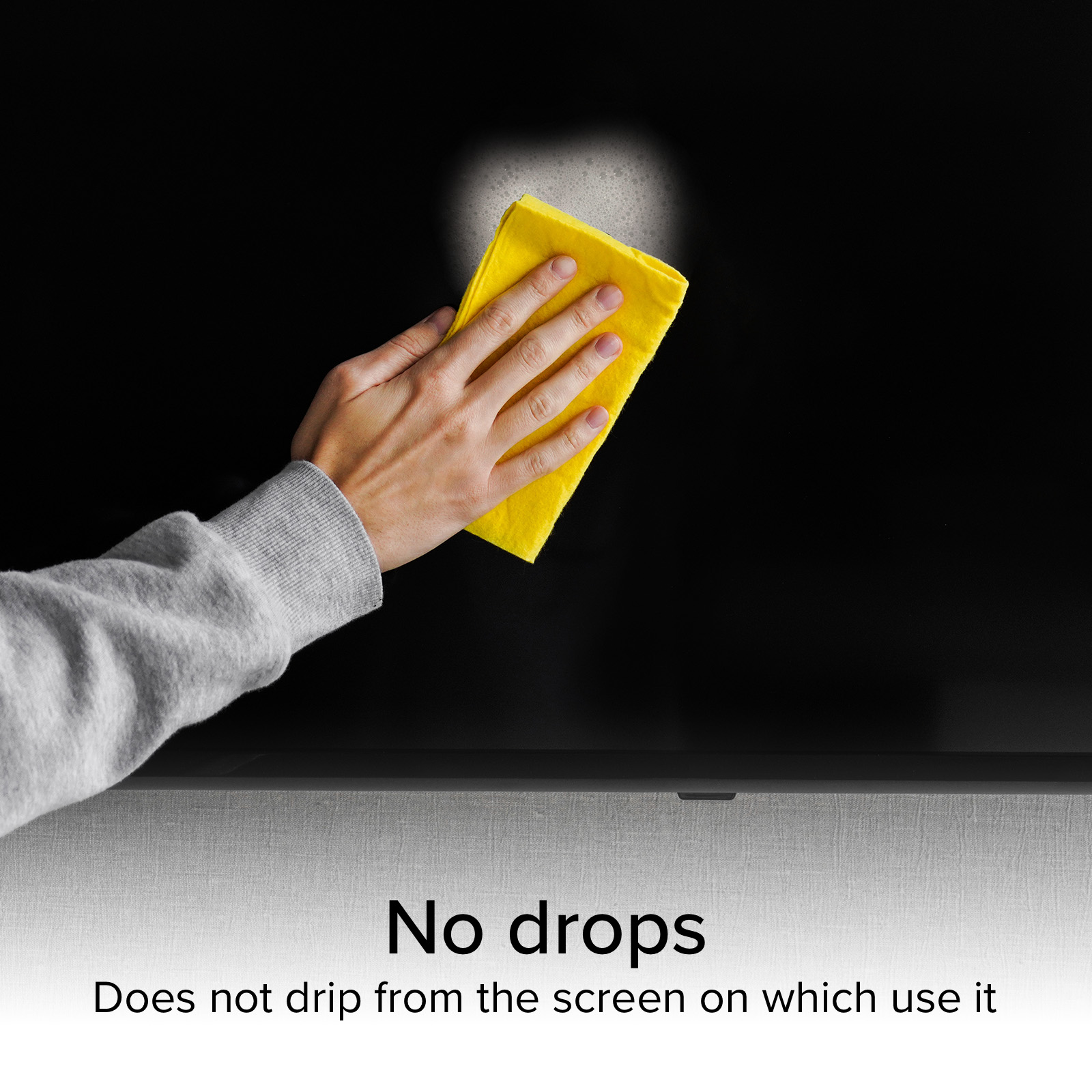 Una mano pulisce uno schermo nero con un panno giallo, creando schiuma.