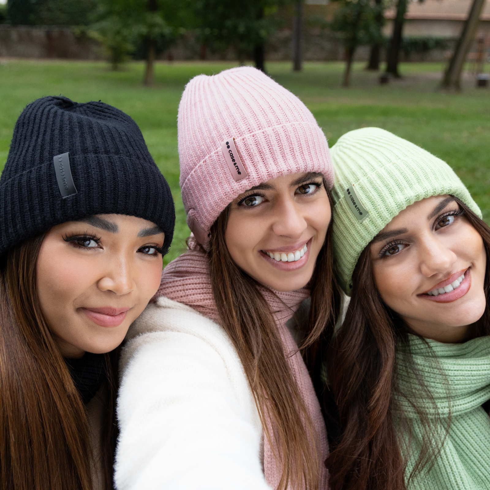 Tre donne indossano cappelli e sciarpe di lana colorati all'aperto.