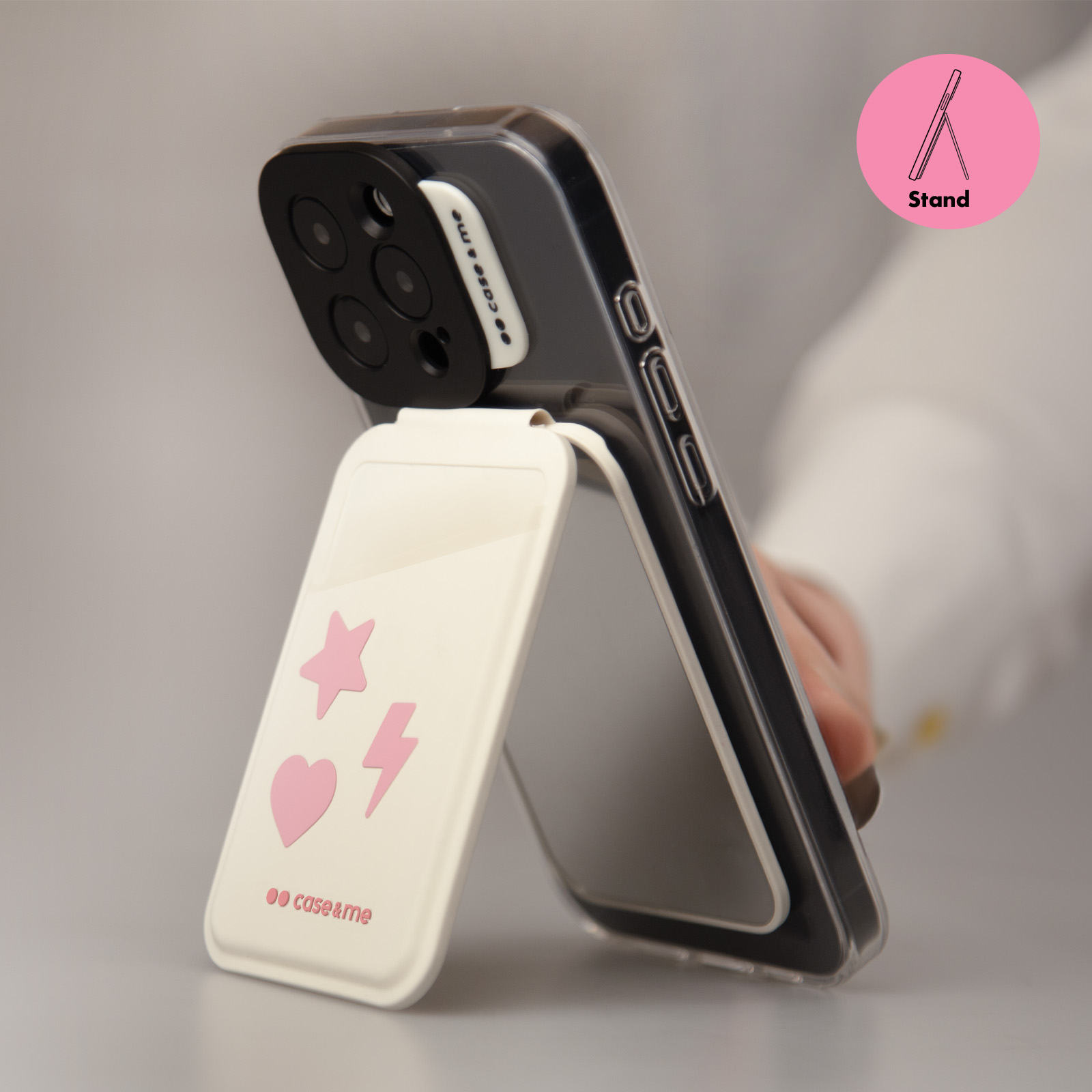 Un teléfono transparente con pegatinas rosas (corazón, estrella, rayo) y soporte.