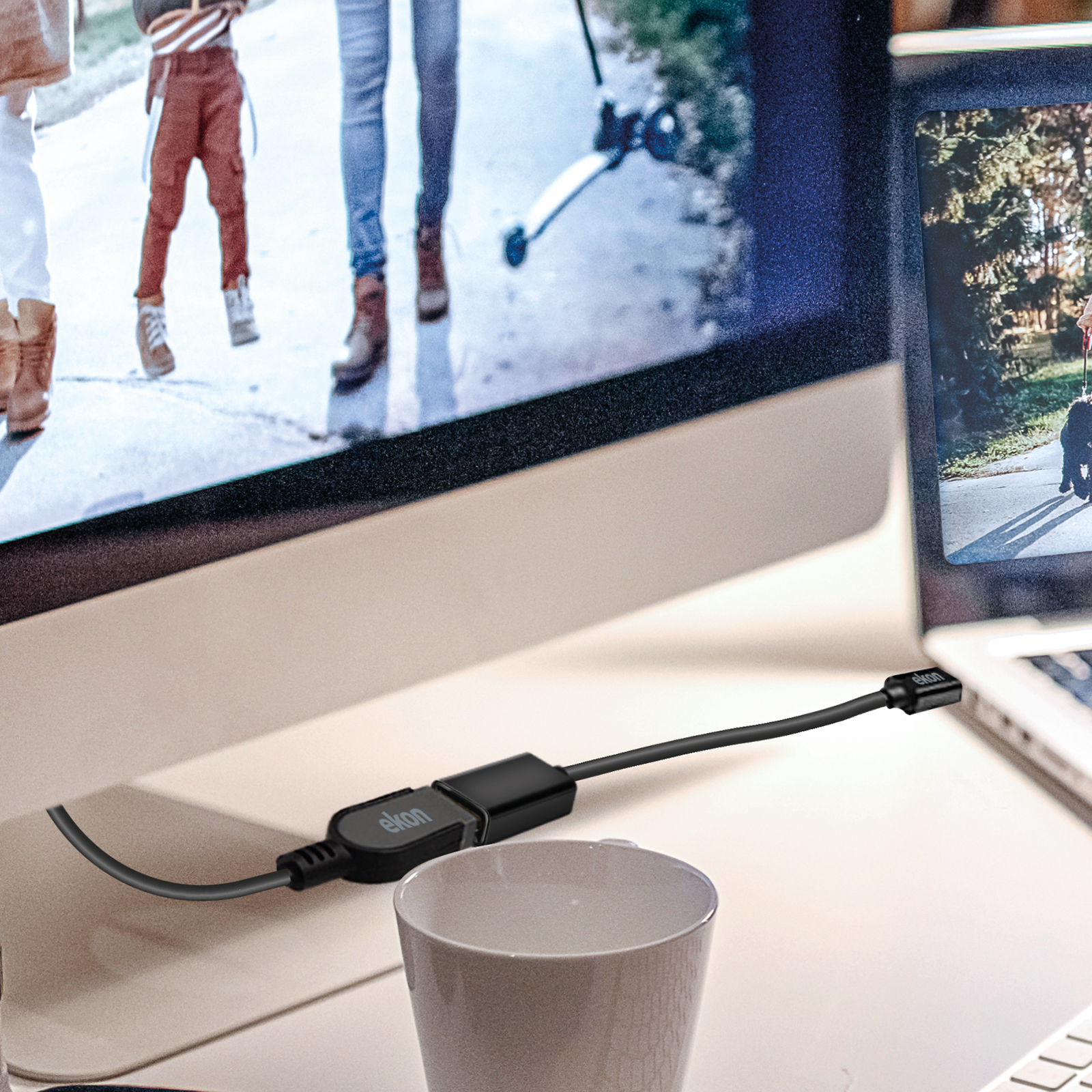 Ein schwarzes Kabel verbindet einen Monitor und einen Laptop. Eine Tasse steht davor.