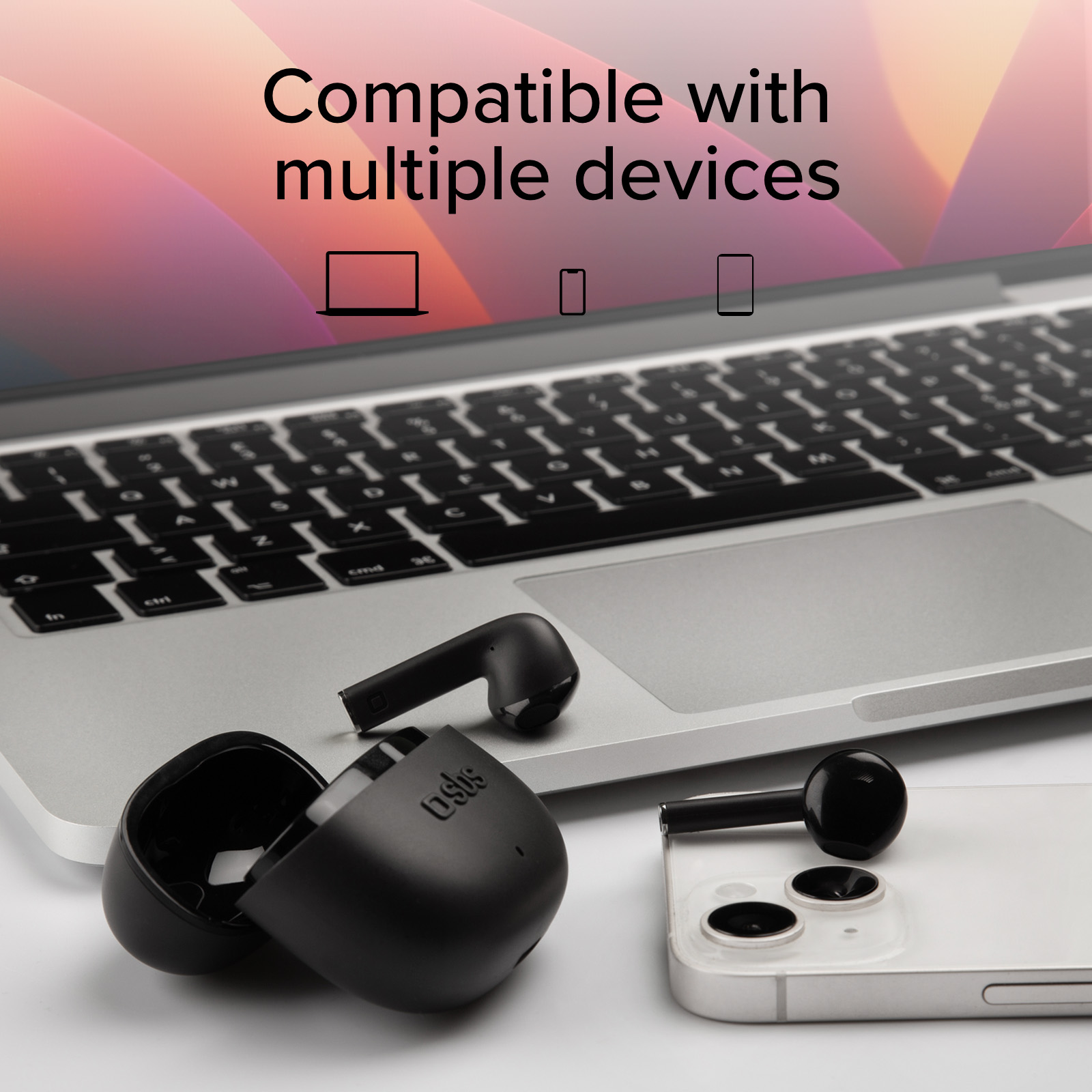 Auricolari neri con custodia di ricarica accanto a un laptop e uno smartphone.
