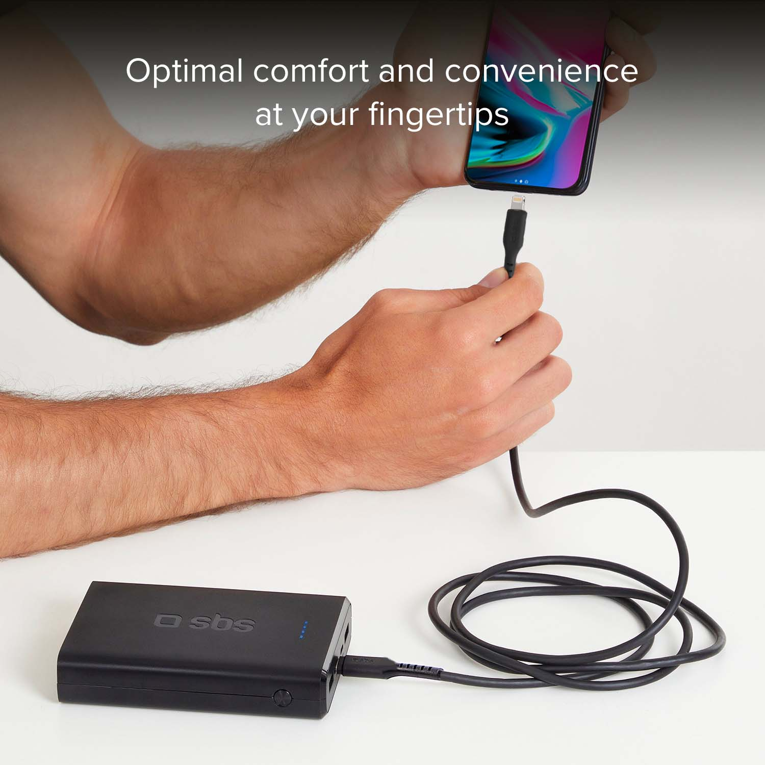 Schwarzes Ladegerät mit Kabel und einem Handy, das von einer Hand gehalten wird.