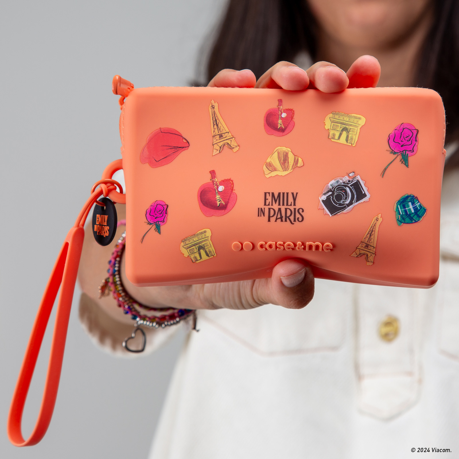 Una bolsa naranja con pegatinas temáticas de París, sostenida por una persona.