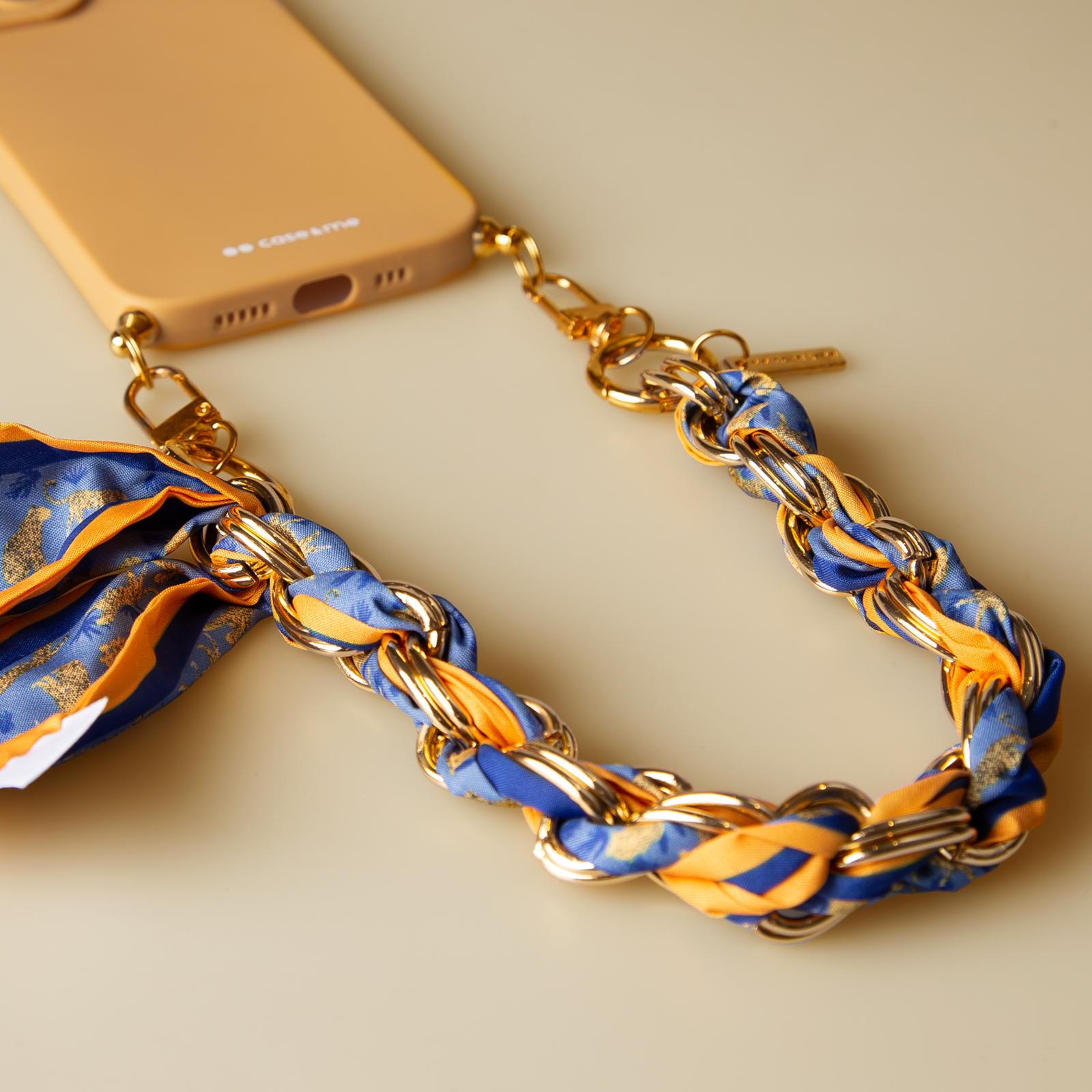 Custodia gialla per telefono con catena dorata e sciarpa blu e gialla.