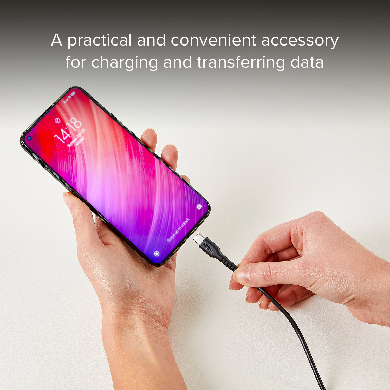 Una mano inserisce un cavo USB-C in uno smartphone con sfondo rosa e viola.