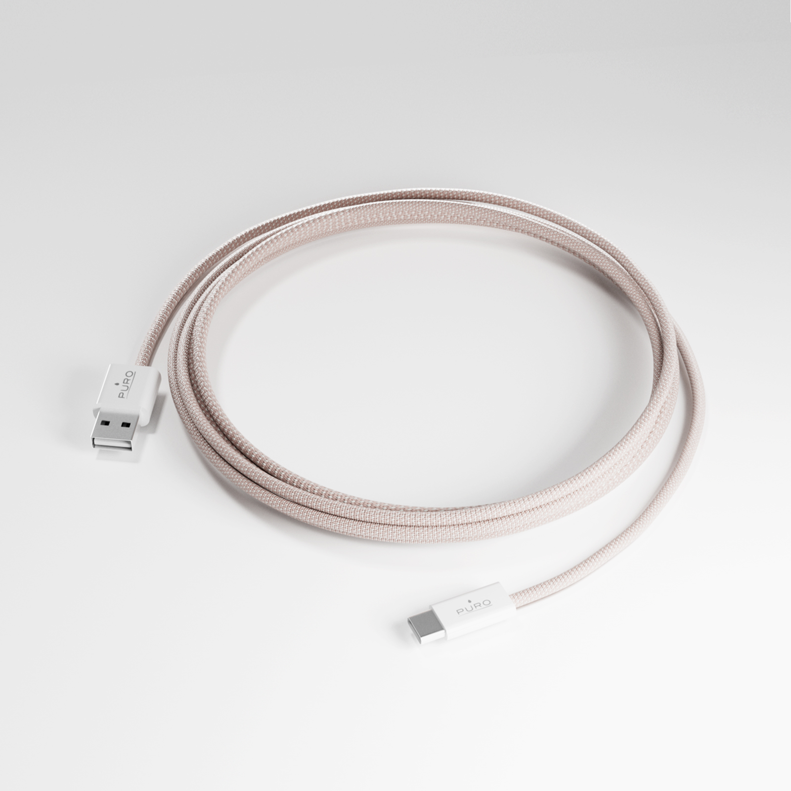 Un cavo USB-C a USB-A intrecciato rosa giace arrotolato su una superficie bianca.