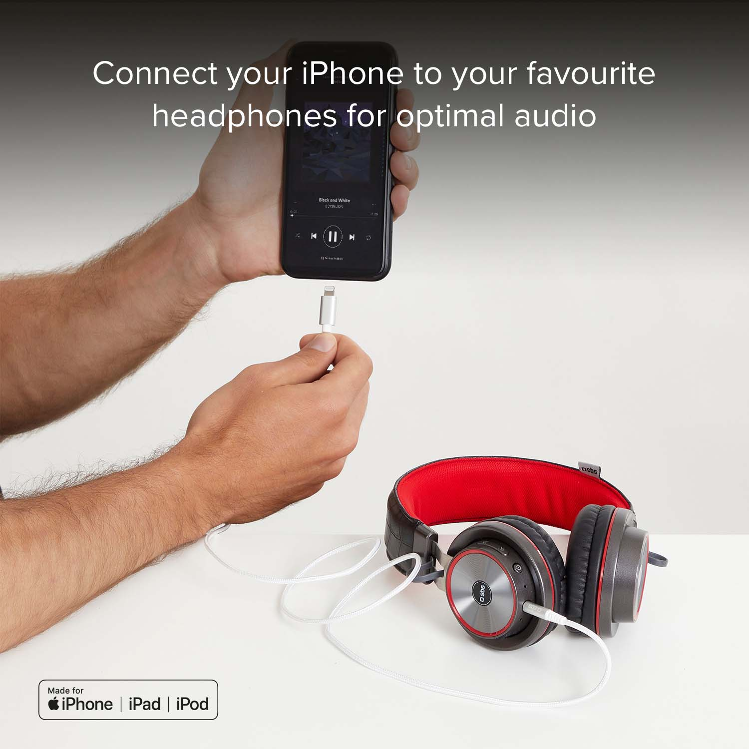 Ein Mann verbindet sein iPhone mit Kopfhörern. Das iPhone zeigt eine Musik-App.