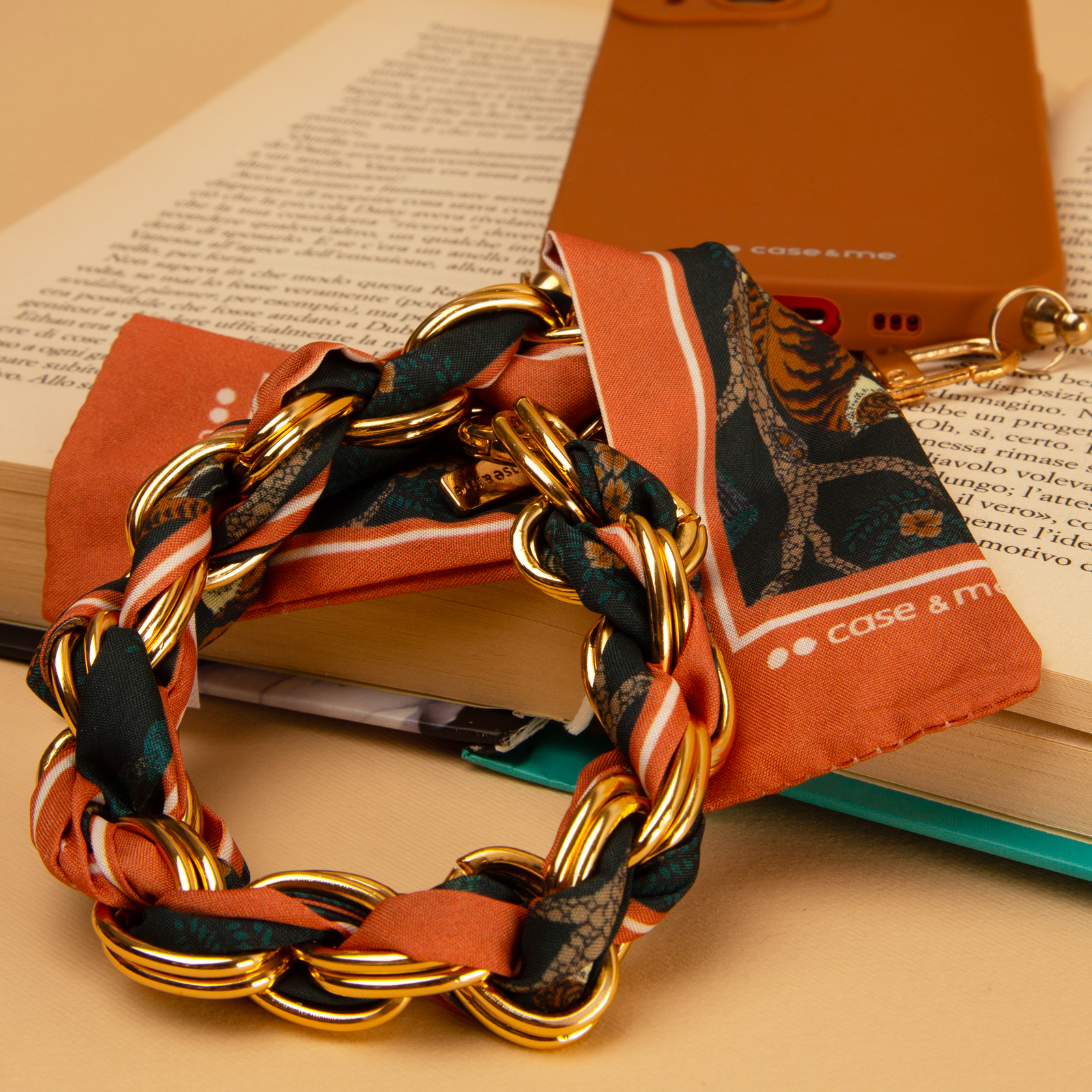 Un collar de cadena dorada con tela estampada naranja sobre un libro abierto.
