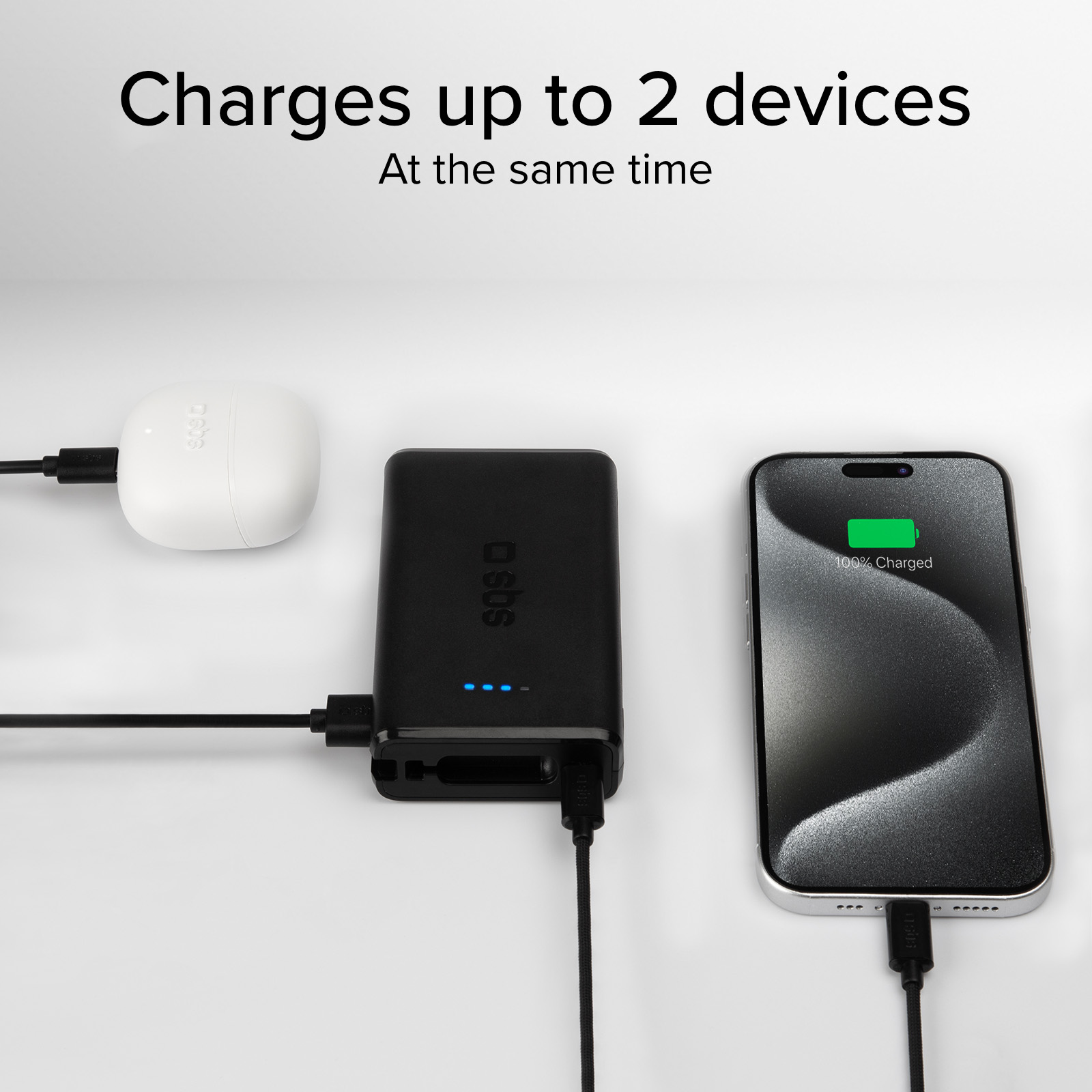 Un caricabatterie bianco, un power bank nero e uno smartphone in carica.