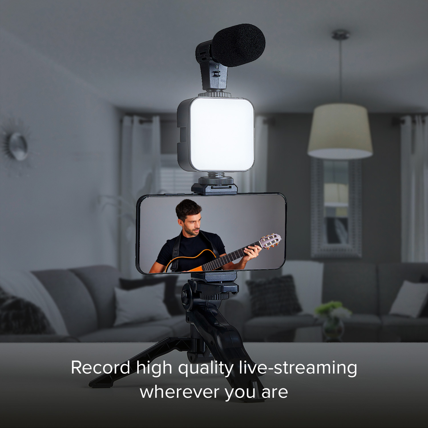 Hombre tocando guitarra, rig de teléfono con micrófono y luz en trípode.