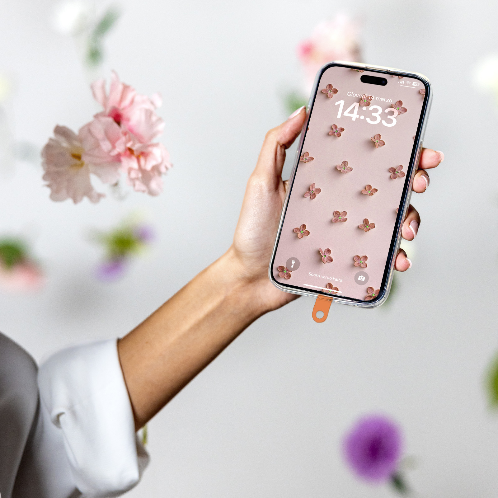 Una mano tiene uno smartphone con motivo floreale. Fiori sullo sfondo.