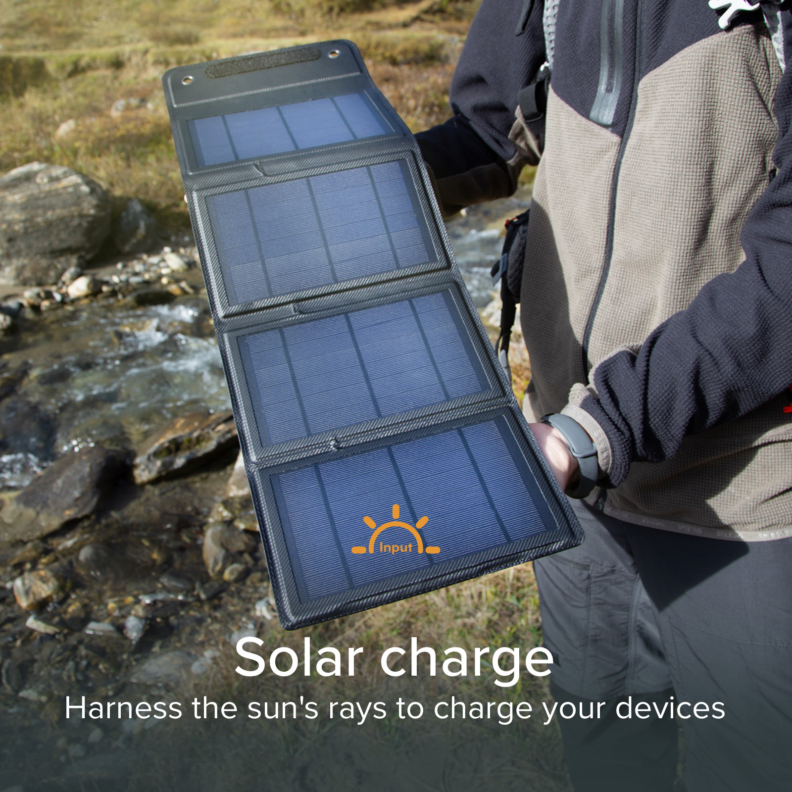 Una persona sostiene un panel solar plegable negro con tres paneles azules al aire libre cerca del agua.