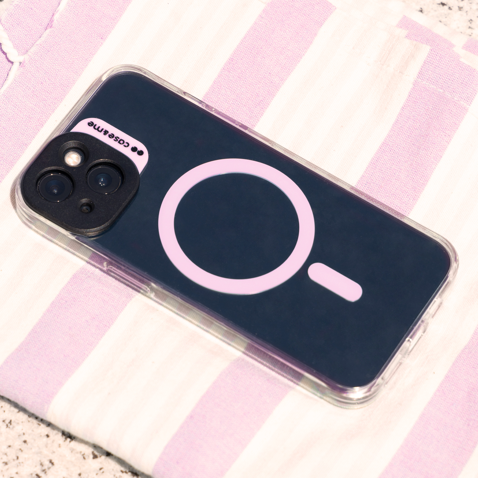 Funda de teléfono azul oscuro con círculo rosa y guion sobre tela rayada.